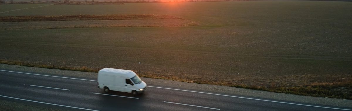 Aerial view of blurred fast moving cargo van driving on highway hauling goods. Delivery transportation and logistics concept.