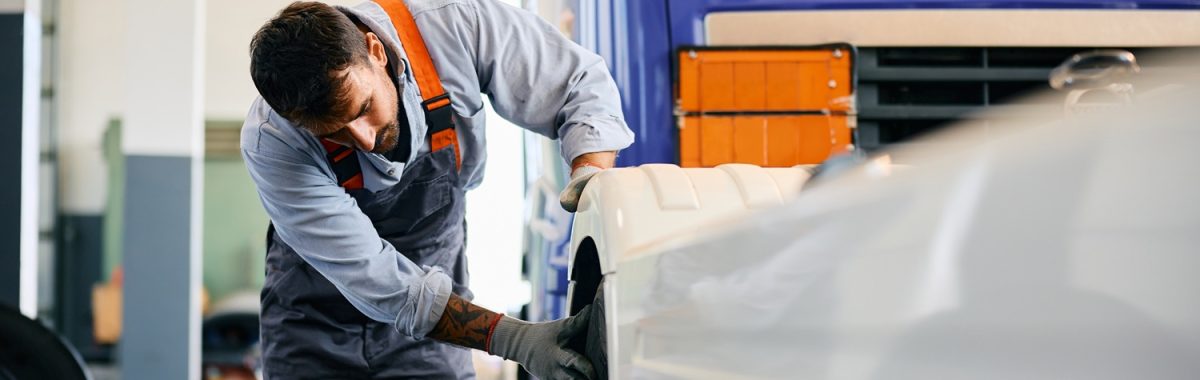 Mechanic checking truck tires while working in repair shop. Copy space.